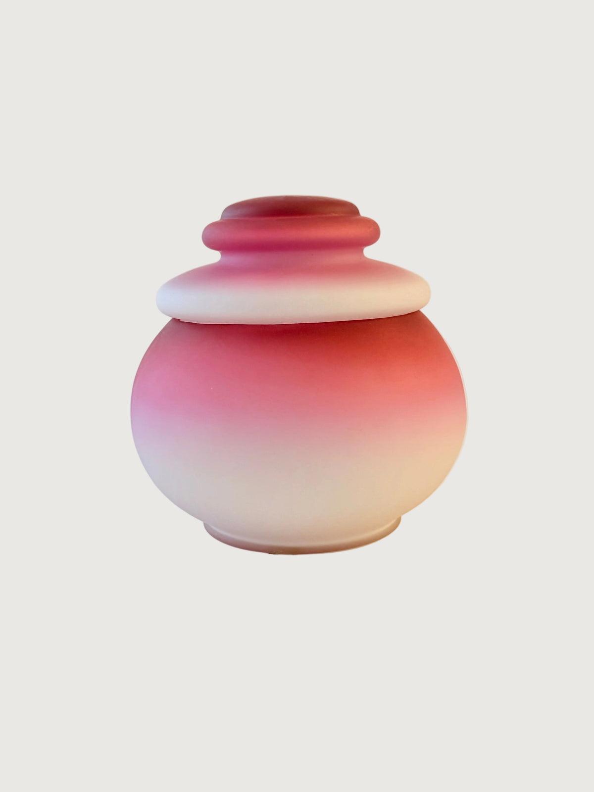 A bulbous  lidded jar with a smooth pink ombre gradient transitioning from deep magenta at the top to soft pink and then white at the base