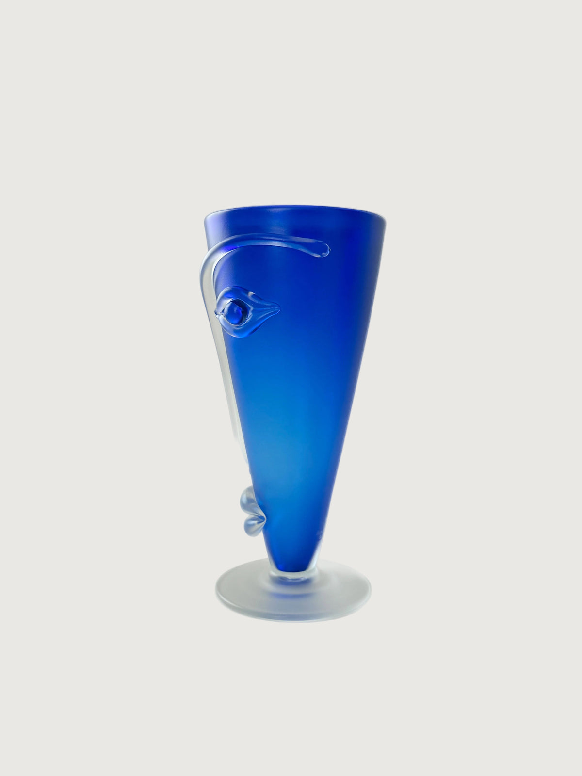 A handblown cobalt blue glass face vase with eyes, nose and mouth. Facing left to show the applied eyes, nose and mouth in clear glass. Home Decor. Vintage. Collectible.