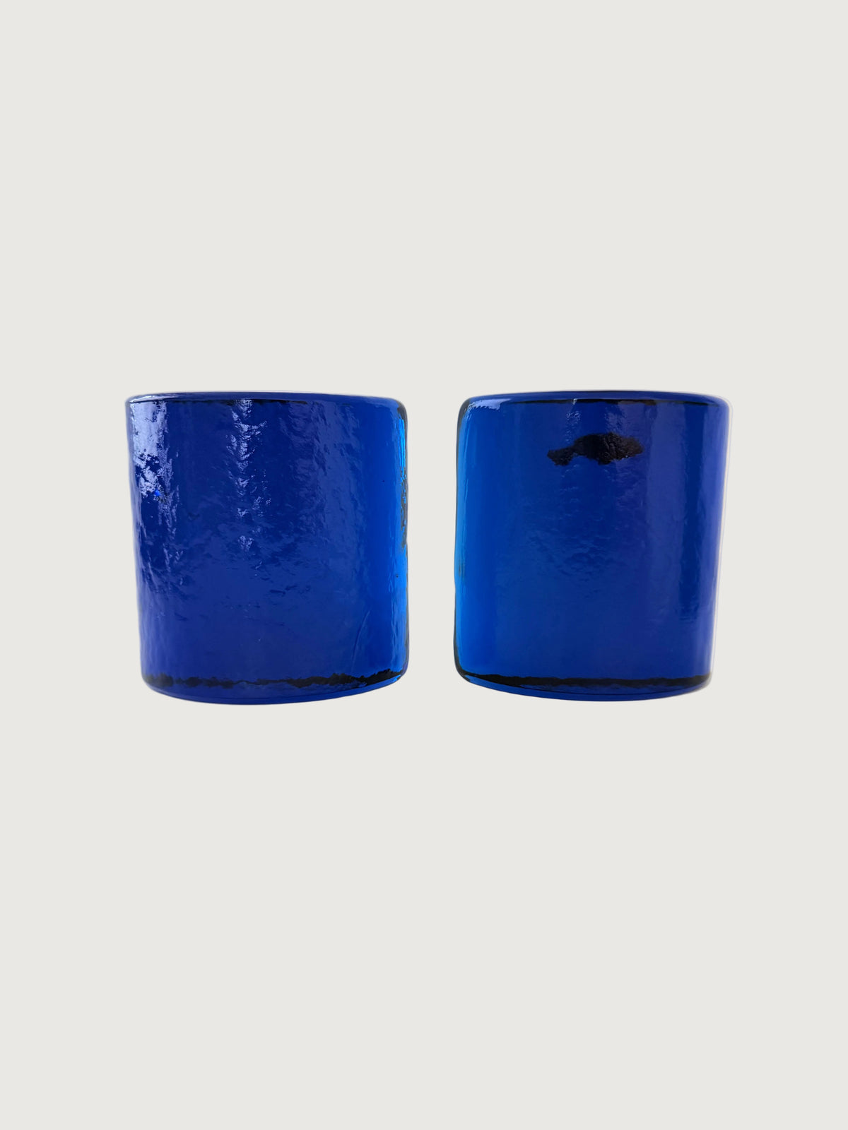 Two cobalt blue textured glass half moon bookends shown side-by-side on a plain off-white background.