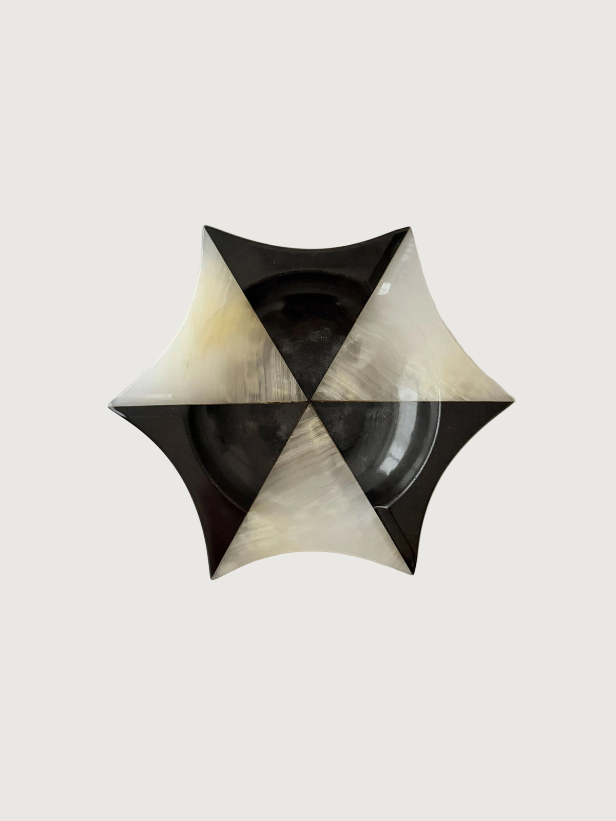 A geometric star-shaped onyx bowl with alternating black and  white marbled sections, photographed from directly above on a plain off-white background. Home Decor. Vintage. Collectible. 