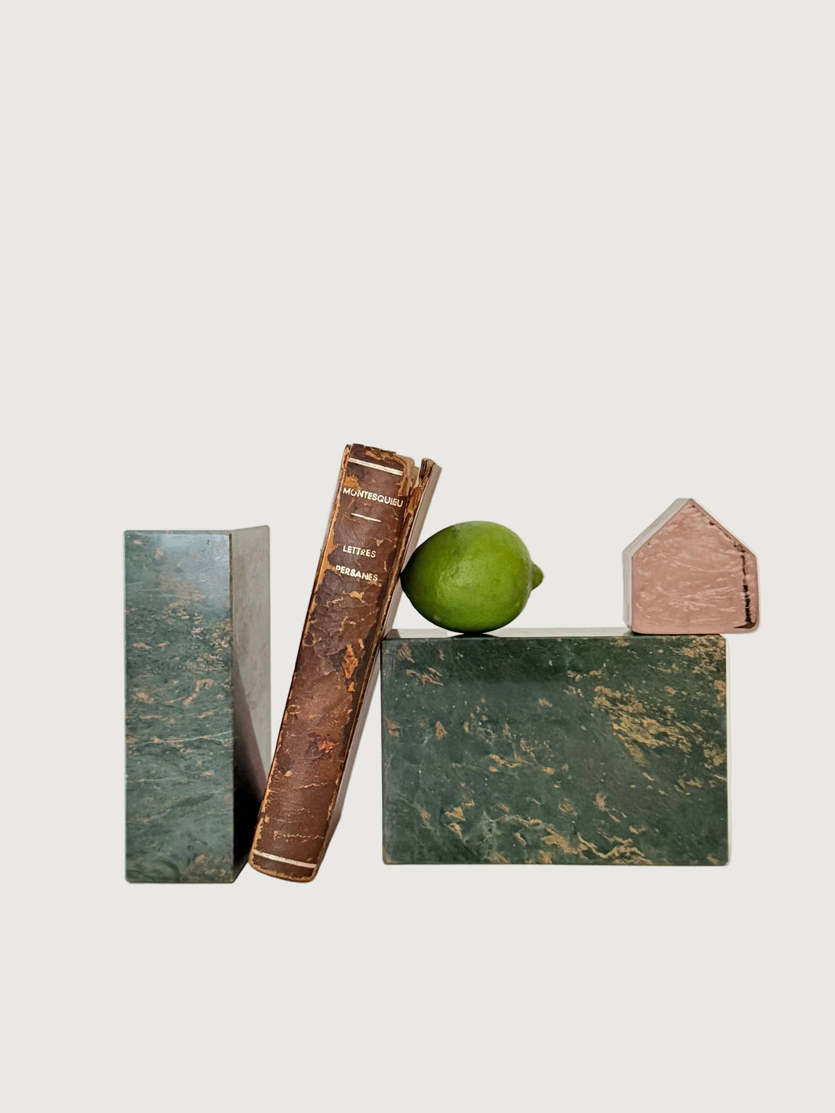 Green salmon rectangular marble bookends styled with a book, a lime and pink glass house.