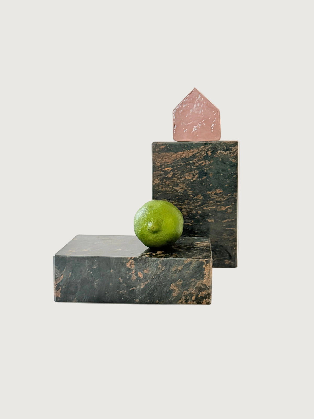 Heavy rectangular green and salmon-colored vintage marble bookends styled with lime and pink glass house.