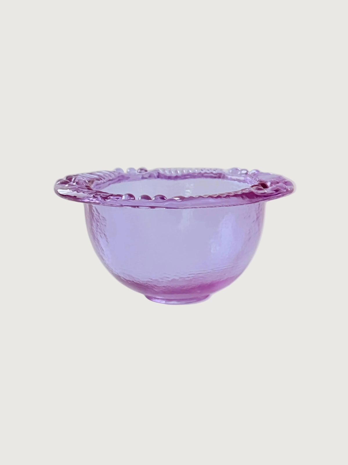 A lavender purple blush glass bowl with a scalloped rim, shown against a solid light gray background.