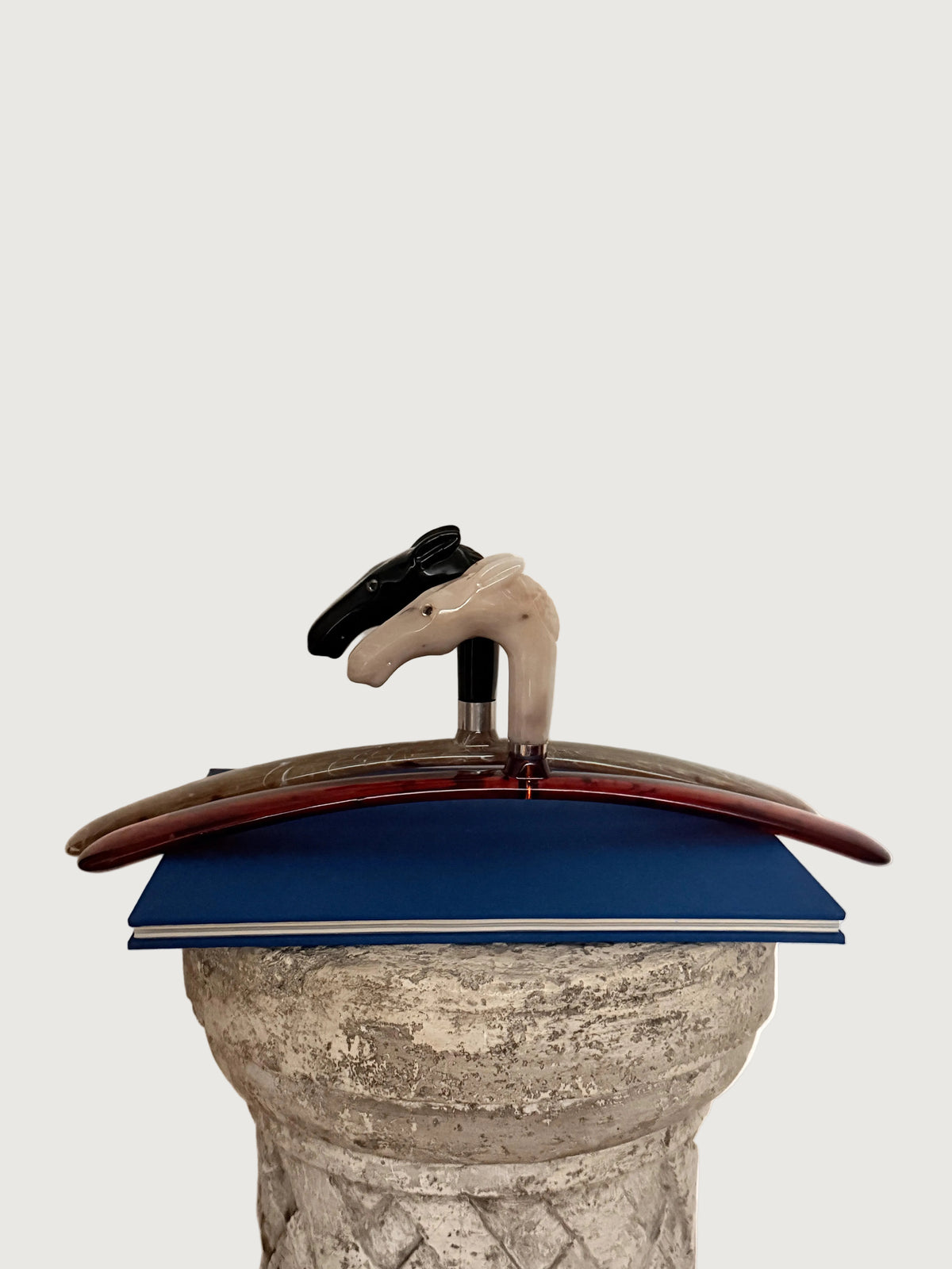 Italian Black and Cream Horse Head  Hangers styled on a pedestal on top of a book