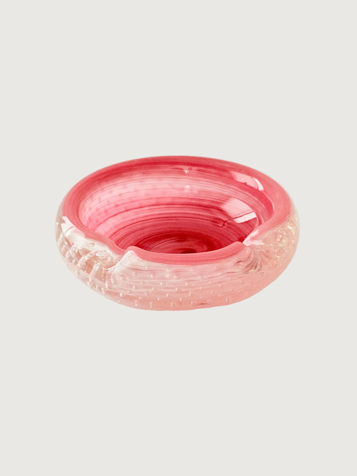 A  round vibrant pink glass ashtray with a textured, bubble-filled design, set against a plain light gray background.Home Decor. Vintage. Collectible. 