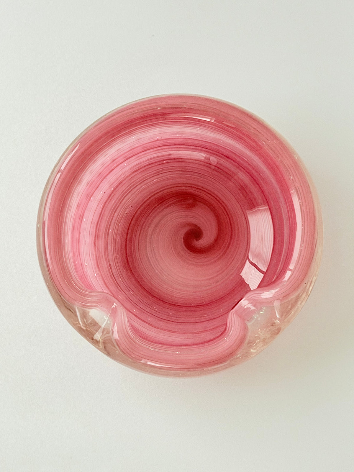 Inside of a  round vibrant pink glass ashtray with a textured, bubble-filled design, set against a plain light gray background.Home Decor. Vintage. Collectible. 