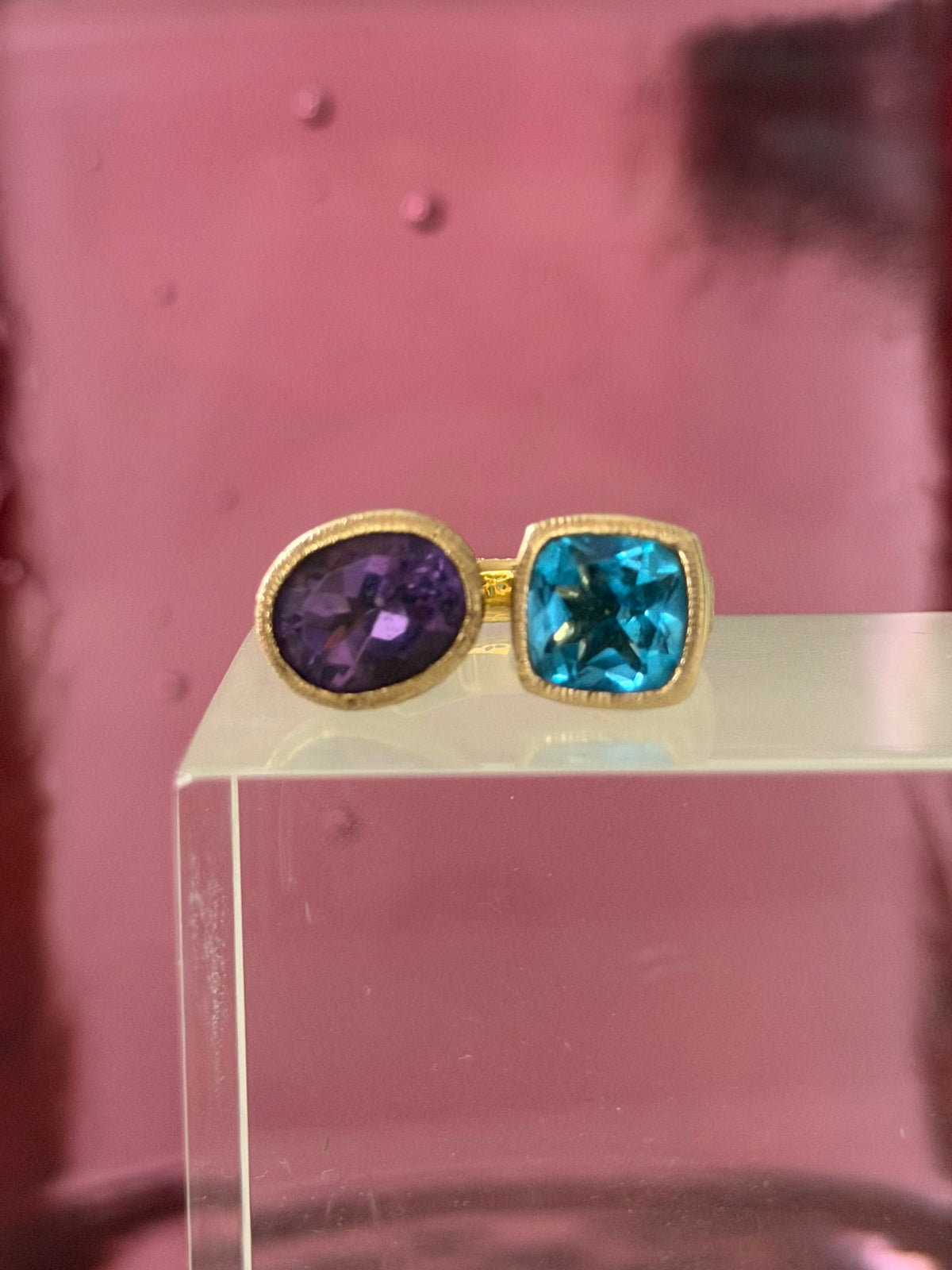An oval purple stone a square bright blue stone set in a vermeil ring.