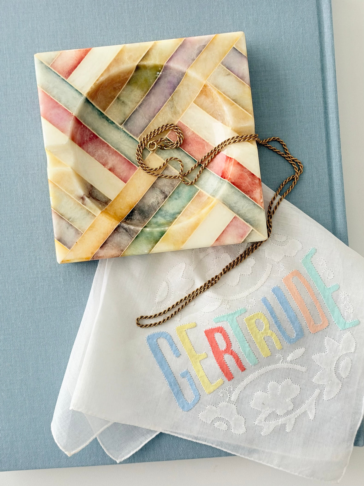 Vintage Colorful Italian Alabaster Catchall on a  light blue book with a handkerchief and necklace